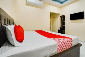 ItwāriOYO Flagship Heritage Farm Resort的一间卧室配有红色和白色枕头的床