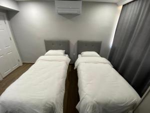 安塔利亚Lara's Suite Antalya的配有白色床单的客房内的两张床