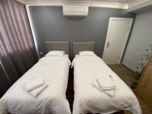 安塔利亚Lara's Suite Antalya的配有白色枕头的客房内的两张床