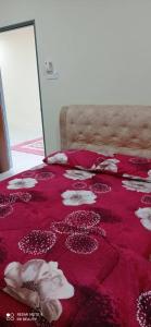 巴佐Homestay CikguRose UMK的一张床上的红色毯子,上面有贝壳