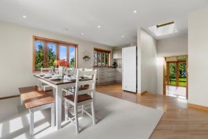 TitirangiBeachside Luxury - Laingholm Holiday Apartment的厨房以及带白色桌椅的用餐室。