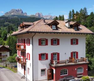 莫埃纳Dolomites Hotel La Meridiana的白色和红色的房子,有红色百叶窗