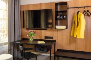 奥贝奈国际之家勤勉酒店的一间设有一张桌子、一台电视和花瓶的房间