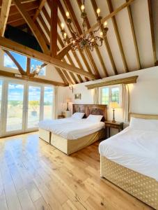 HardhamThe Mill House on the Brooks South Downs West Sussex Sleeps 15的客房设有两张床铺、木制天花板和窗户。