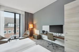 明斯特H4明斯特酒店的酒店客房设有一张床和一张带电视的书桌。
