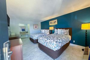 哈蒂斯堡Paradise Inn By OYO Hattiesburg North的一间卧室设有两张床和蓝色的墙壁
