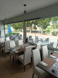 布里阿尔Auberge du pont canal的餐厅设有桌椅和大窗户。