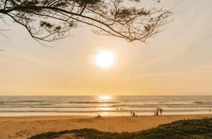 卡伦海滩Phuket Emerald Beach Resort的日落时分在海滩上一群人