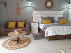 埃祖尔韦尼Damicha Boutique Lodge的一间卧室配有一张床、一张桌子和一张沙发