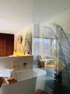 魏勒格Orange Lounge的浴室设有玻璃墙、水槽和浴缸