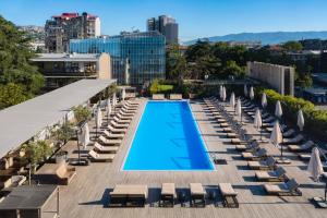 第比利斯第比利斯假日酒店 的一座带躺椅的建筑屋顶上的游泳池