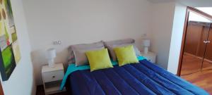 布埃乌Ático de Ana的一间卧室配有蓝色的床和黄色枕头