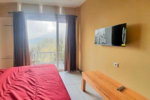 岩望Delvia Bromo Homestay Mitra RedDoorz的卧室配有一张床,墙上配有电视。