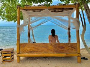 Tintipan IslandEl Cocotal Tintipán By Ashram的坐在海滩上床边的女人
