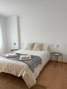 坎加斯德穆拉索Alojamiento céntrico en Cangas的白色卧室配有一张大床和两张桌子