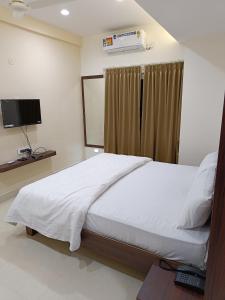 班加罗尔RK COMFORTS的卧室配有白色的床和电视。
