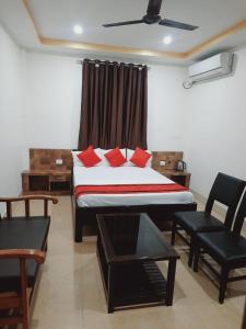 古瓦哈提Hotel Knight Inn Airport的一间卧室配有一张带红色枕头的床和一把椅子