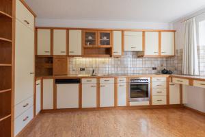 梅劳Haus Helena的厨房铺有木地板,配有白色橱柜。