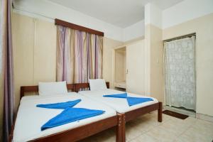 蒙巴萨Mombasa Railway Gardens Hotel的一间卧室配有两张床和蓝色毛巾。