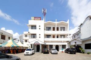 蒙巴萨Mombasa Railway Gardens Hotel的白色的建筑,有汽车停在停车场