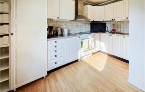 永比Amazing Home In Ljungby With Harbor View的厨房铺有木地板,配有白色橱柜。