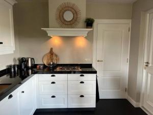 Ambt DeldenVakantiehuisje de Wender的厨房配有白色橱柜和黑色台面