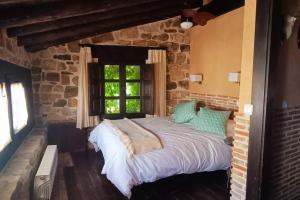 比努埃萨Casa Rural con encanto en plena Reserva de Urbión.的卧室配有一张石墙内的大床