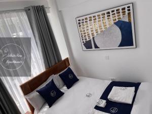 MeruWhiteRose Apartments的一间卧室配有一张带蓝色和白色枕头的床