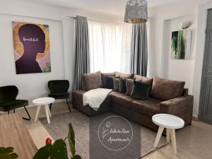 MeruWhiteRose Apartments的客厅配有棕色沙发和2张桌子