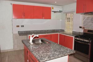 阿克拉FREDA'S COURT的一间带红色橱柜和水槽的厨房