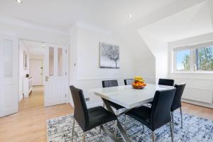 巴尔内特Modern, Bright, Spacious 2 Bed 2 Bath Barnet Penthouse By 360Stays的一间配备有白色桌子和黑色椅子的用餐室
