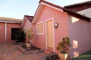 卡达斯诺瓦斯Pousada Caldas Novas的粉红色的房子,有黄色的门和一些树木