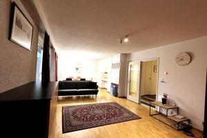 迪本多夫Cosy 4.5 rooms apartment @ LS 16 Dübendorf的客厅配有黑色沙发和地毯。