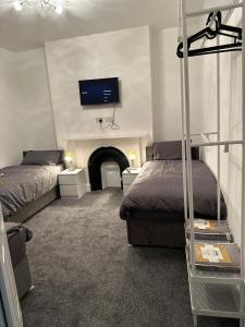 艾纯查姆5-Bed Apartment in Altrincham near airport的一间卧室设有两张床,墙上配有电视。