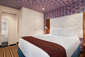 纽约Night Hotel Broadway的一间卧室配有一张大床和紫色墙壁