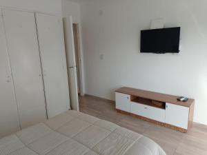 维森特洛佩斯Lovely one bedroom apartment in Vicente Lopez的一间卧室配有一张床,墙上配有电视