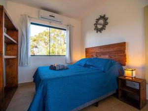 普腊亚罗萨Lugar ao Sol - Flats - Praia do Rosa - SC的一间卧室设有蓝色的床和窗户。