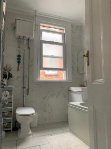 Harrow on the Hill38 Whitehall Road的白色的浴室设有卫生间和窗户。