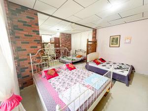 峇六拜Dusun Indah Cottage 2的一间卧室设有两张床和砖墙