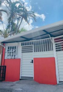 圣何塞Apartamento-San José-WiFi的一个带红色和白色门的车库,棕榈树