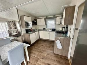 Kinmel Bay6 berth luxury caravan, Lyons Winkups Holiday Park的小厨房配有白色橱柜和桌子