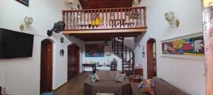 佩鲁伊比Casa Rosa de Peruíbe - Casa de Temporada 3 dormitórios, 10 hóspedes, piscina, wi-fi, netflix, 800 metros da praia的一间带楼梯和沙发的客厅