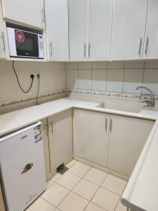 Al Ḩawīyahطرف الطريق的厨房配有白色橱柜、水槽和微波炉