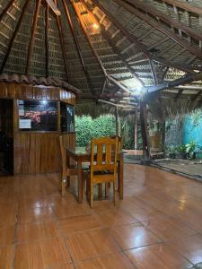 帕克拉Mauras Tropical Mini Hostel & Tours的一张桌子和椅子坐在屋顶下