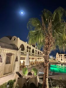 卢克索Elphardous Oasis Hotel的棕榈树在晚上在建筑物前