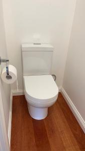 墨尔本Melbourne Inner City Holiday Home Near CBD & Flemington的浴室铺有木地板,设有白色卫生间。