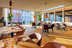 哥本哈根NH Collection Copenhagen的餐厅设有木桌和椅子以及大窗户。