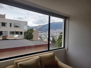 基多Lujoso apartamento en Bellavista的客厅设有大窗户,享有城市美景