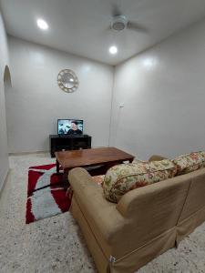 马六甲Homestay Melaka Baitul Saadah的带沙发、桌子和电视的客厅