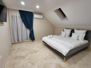 阿拉德Sika Palladium Central Apartment的卧室配有一张带蓝色窗帘的大型白色床